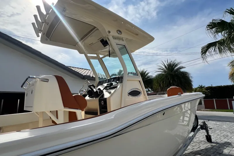 Slide: The Image of 2014 Scout 245 XSF boat with sleek design, parked outdoors under a sunny sky. - 29