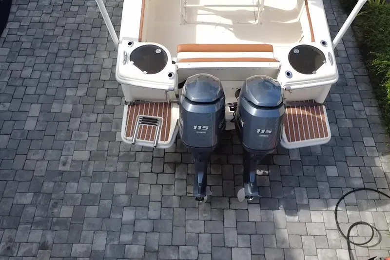 Slide: The Image of 2014 Scout 245 XSF boat with twin 115 horsepower outboard engines on a paved surface. - 5