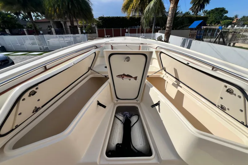 Slide: The Image of 2014 Scout 245 XSF boat interior with open storage compartments and palm trees in the background. - 78