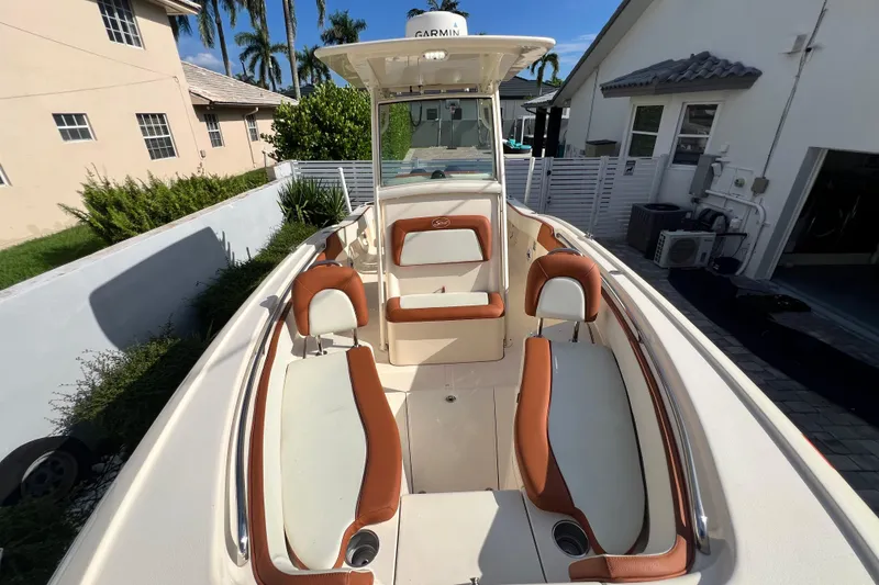 Slide: The Image of 2014 Scout 245 XSF boat with brown and white seating, docked near residential homes. - 76