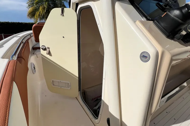 Slide: The Image of 2014 Scout 245 XSF boat interior with open cabin door, showcasing seating and controls. - 61