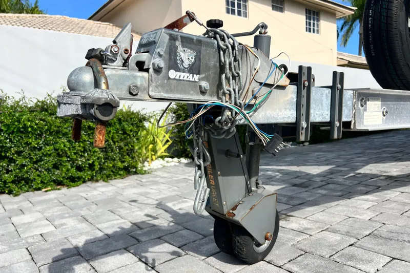 Slide: The Image of Trailer hitch and wheel assembly for 2014 Scout 245 XSF boat on paved driveway. - 23