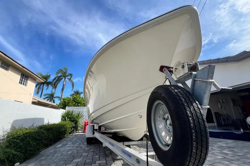 Slide: The Image of 2014 Scout 245 XSF boat on trailer, parked in driveway under clear blue sky. - 27