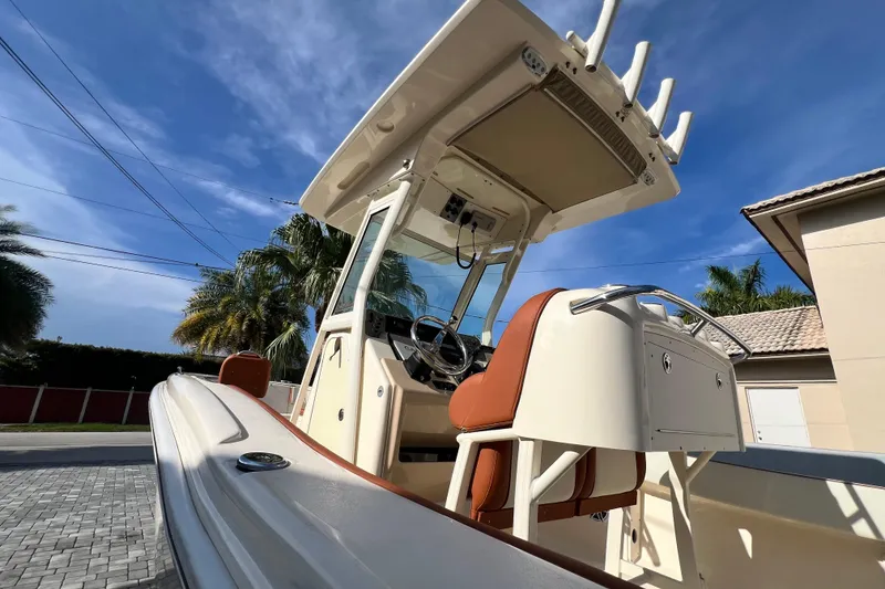Slide: The Image of 2014 Scout 245 XSF boat with center console, parked near palm trees and houses. - 88