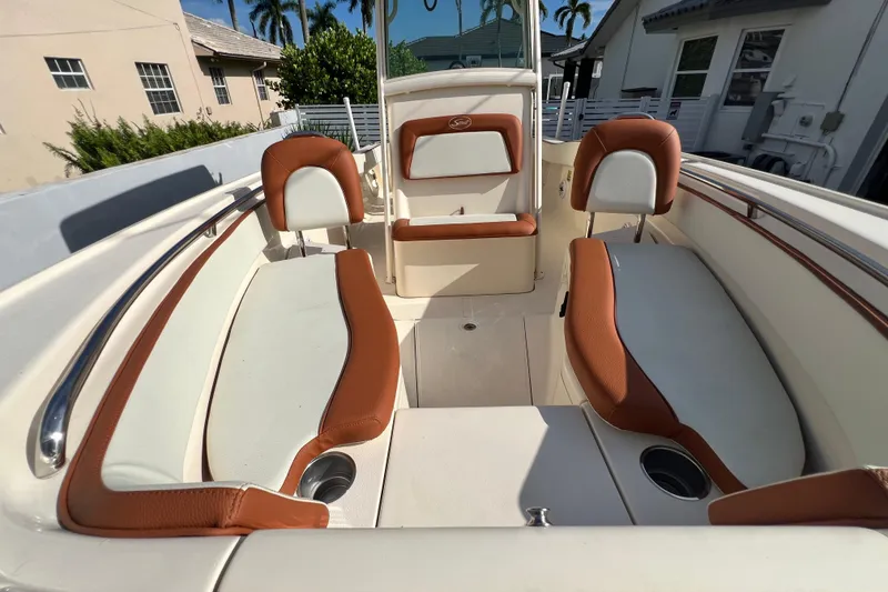 Slide: The Image of 2014 Scout 245 XSF boat interior with brown and white seating, cup holders, and sunny deck. - 75