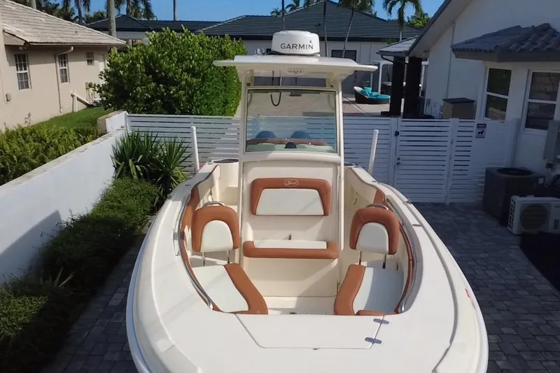 Slide: The Image of 2014 Scout 245 XSF boat with tan seating, parked in a residential driveway. - 17