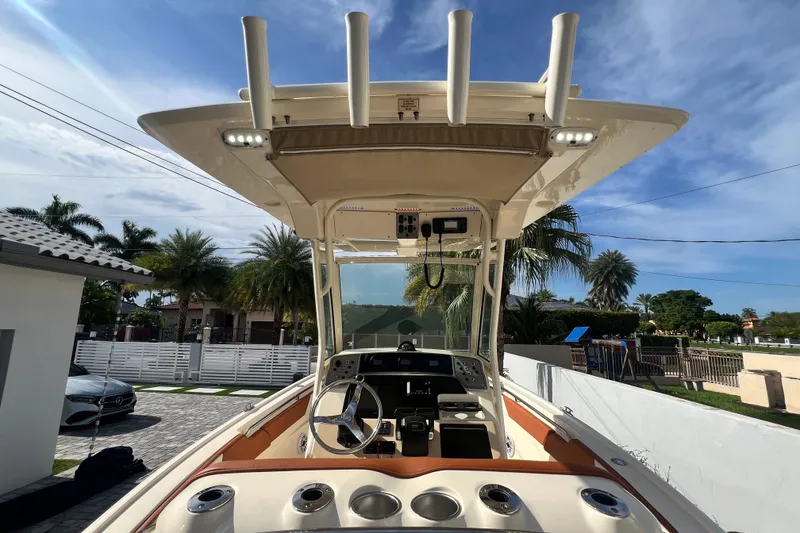 Slide: The Image of 2014 Scout 245 XSF boat with T-top and steering console, parked outdoors. - 50