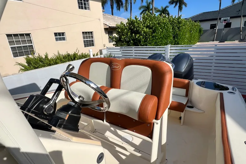 Slide: The Image of 2014 Scout 245 XSF boat interior with steering wheel and seating, parked outdoors. - 62