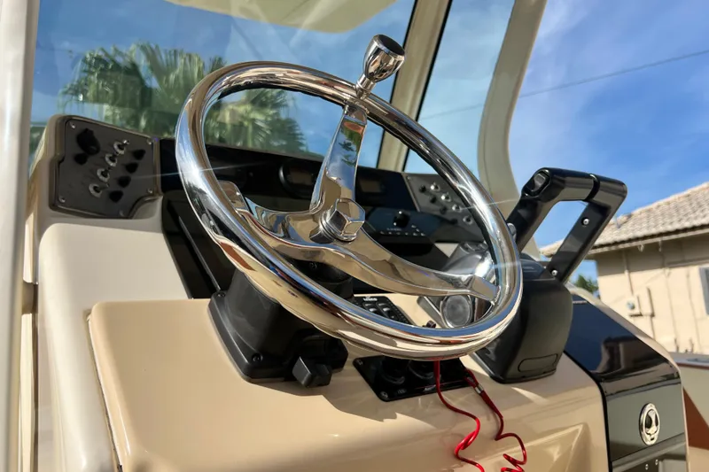 Slide: The Image of Steering wheel of a 2014 Scout 245 XSF boat, showcasing control panel and throttle. - 58