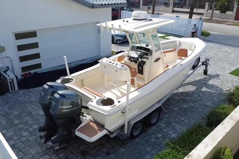 Slide: The Image of 2014 Scout 245 XSF boat with dual Yamaha engines on a trailer in driveway. - 15