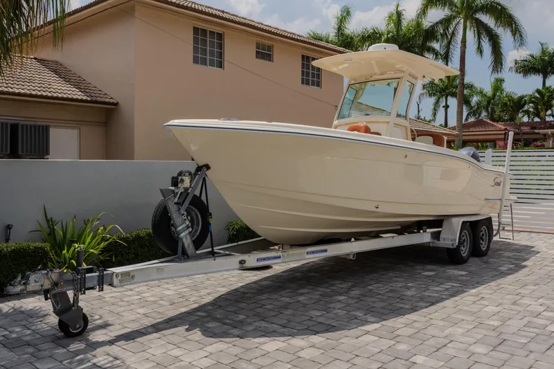 Slide: The Image of 2014 Scout 245 XSF boat on trailer in residential driveway with palm trees. - 2