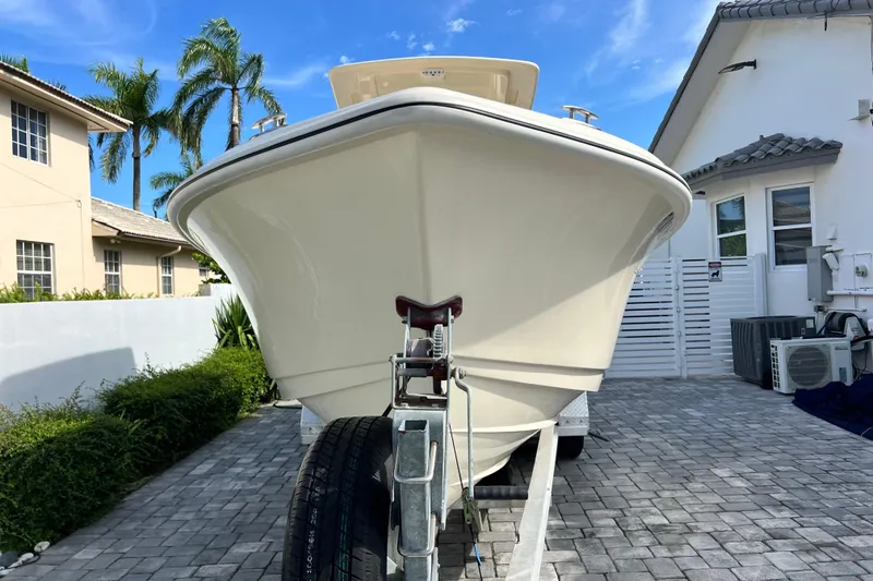 Slide: The Image of 2014 Scout 245 XSF boat on trailer in residential driveway, surrounded by palm trees. - 26