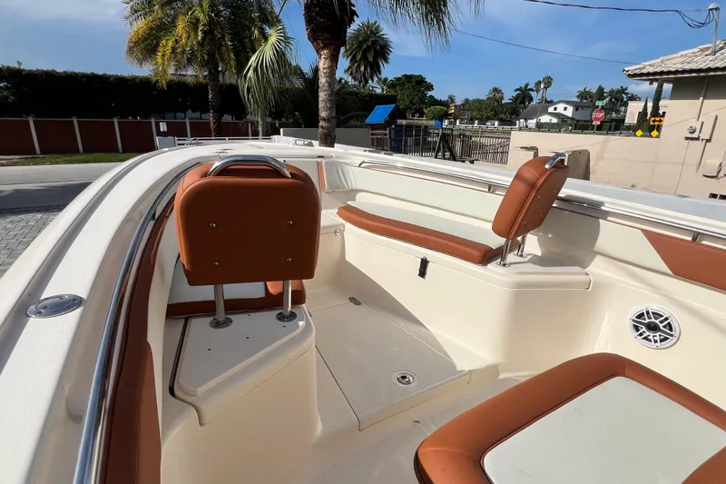 Slide: The Image of 2014 Scout 245 XSF boat interior with brown seating and palm trees in the background. - 67