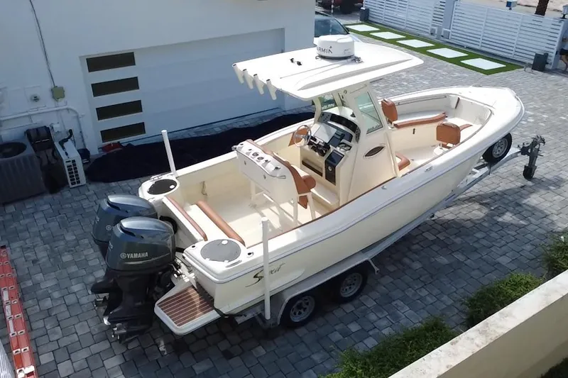 Slide: The Image of 2014 Scout 245 XSF boat with dual Yamaha engines on a trailer in a driveway. - 3