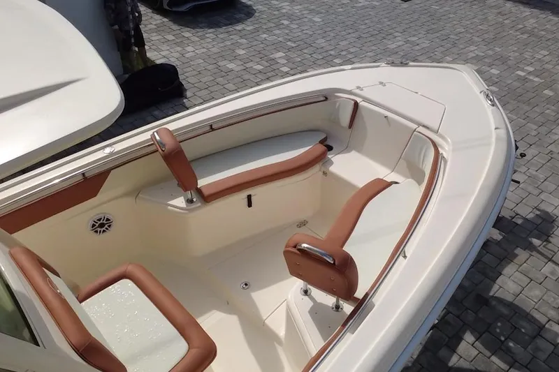 Slide: The Image of 2014 Scout 245 XSF boat interior with brown and white seating on a paved surface. - 12