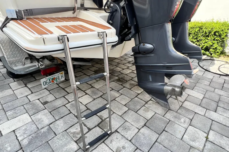 Slide: The Image of 2014 Scout 245 XSF boat with ladder and dual outboard motors on a paved surface. - 40