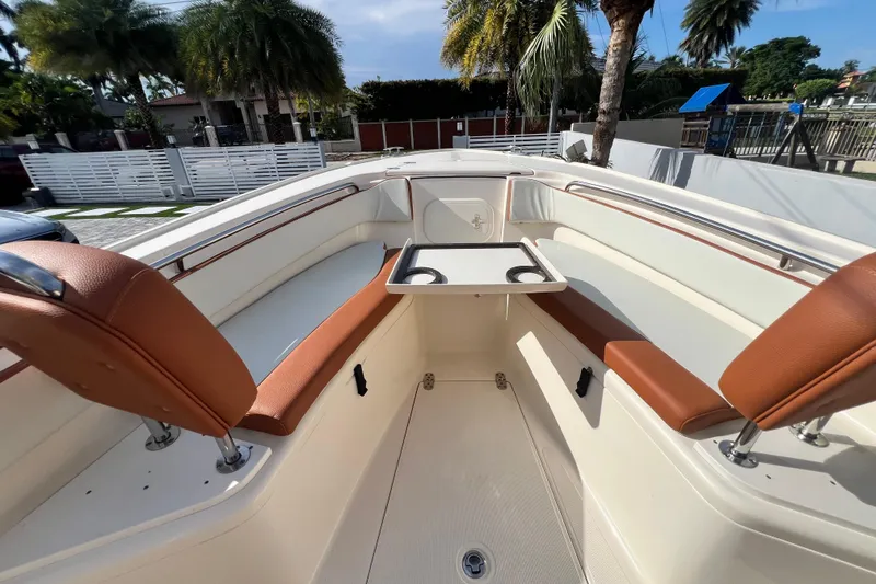 Slide: The Image of 2014 Scout 245 XSF boat interior with seating and table, surrounded by palm trees. - 70