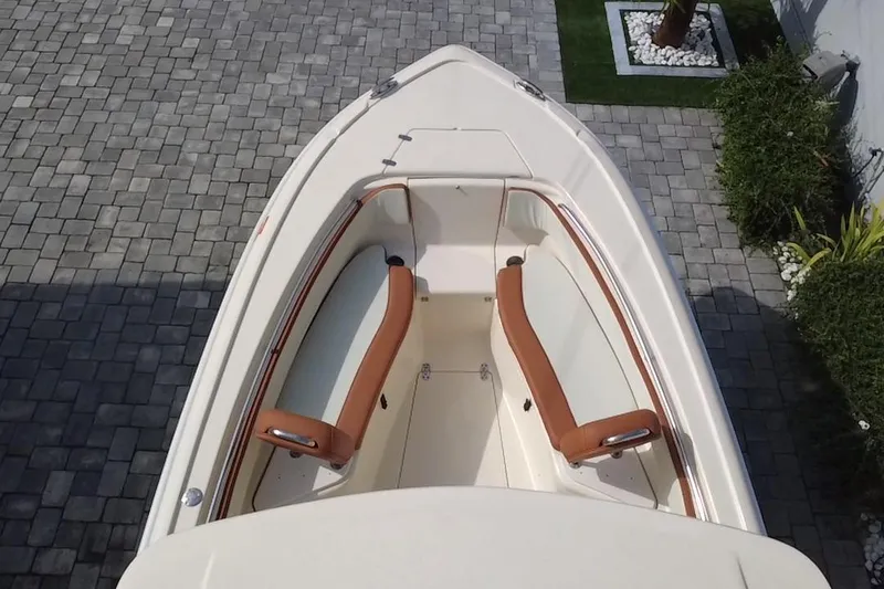 Slide: The Image of 2014 Scout 245 XSF boat with tan seating, viewed from above on a paved surface. - 13