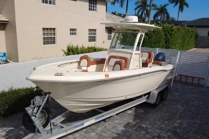 Slide: The Image of 2014 Scout 245 XSF boat on trailer, parked in a residential driveway. - 19