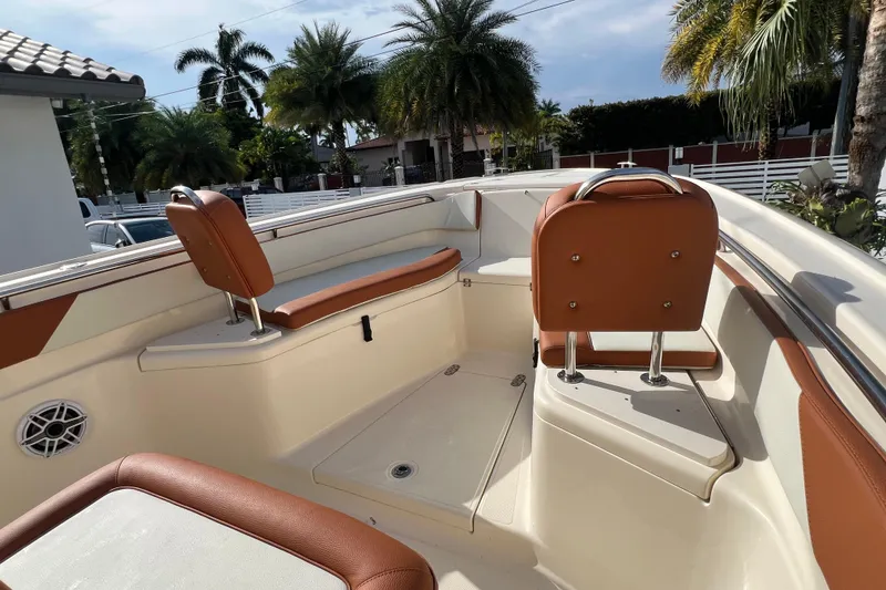 Slide: The Image of 2014 Scout 245 XSF boat interior with brown seating and palm trees in the background. - 66