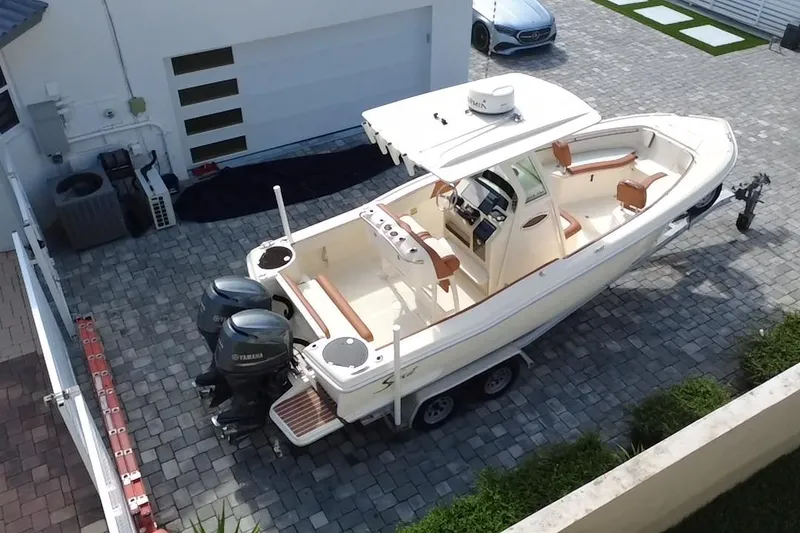 Slide: The Image of 2014 Scout 245 XSF boat with dual Yamaha engines on a trailer in a driveway. - 4