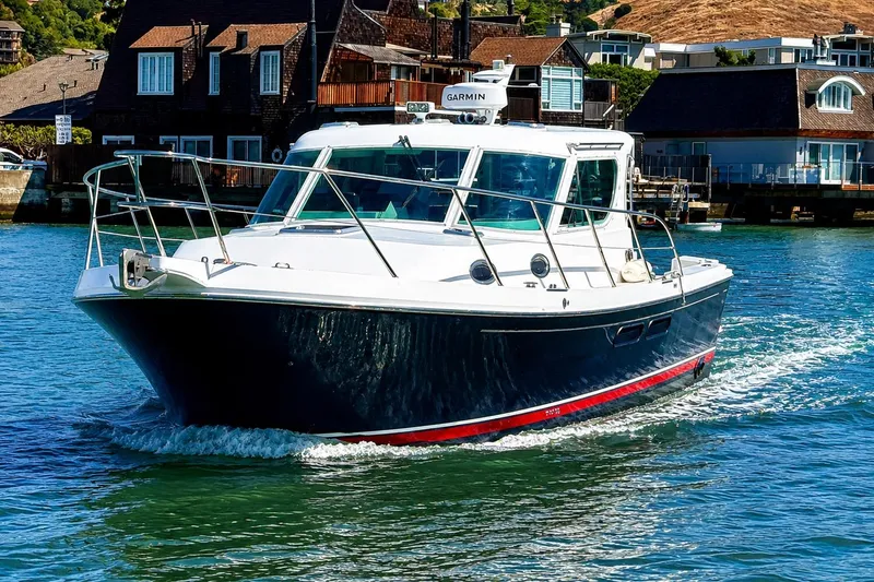 Slide: The Image of 2005 Compton 33 Downeast Express boat cruising on water near waterfront homes. - 2
