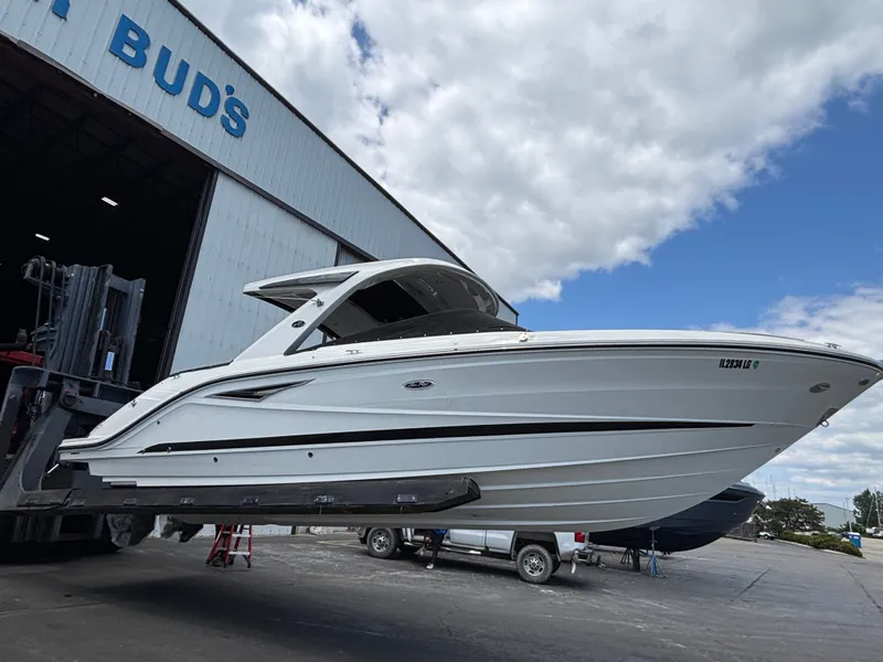 The Image of A 2024 Sea Ray SLX 310 boat being lifted from a warehouse. It is white with sleek lines. - 0