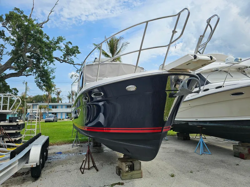 Slide: The Image of A 2021 Cutwater C-28 boat is parked on a lot. It features a dark blue hull with a red stripe. - 2