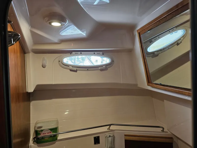Slide: The Image of The image shows the bathroom of a 2021 Cutwater C-28 with a porthole and mirror. - 21