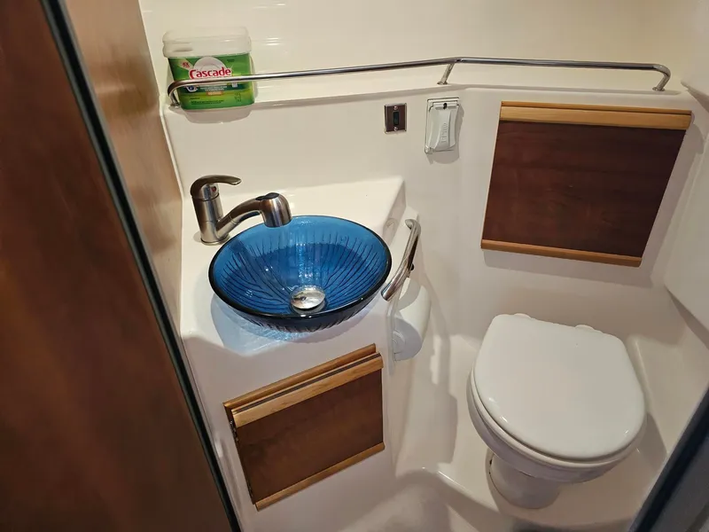 Slide: The Image of The image shows a boat bathroom with a blue glass sink and a toilet. - 22