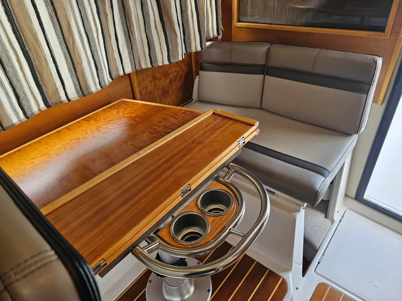 Slide: The Image of Interior of a 2021 Cutwater C-28 with a wooden table and gray upholstered seating. - 16