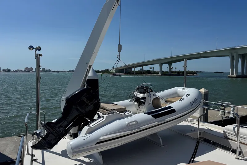 Slide: The Image of 2015 Hampton Endurance yacht with a small boat on deck, near a bridge over calm waters. - 91