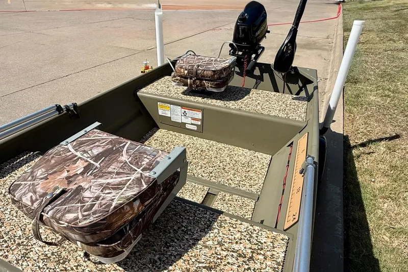 Slide: The Image of 2026 Tracker Grizzly 12 Jon boat with camo seats and motor, parked on pavement. - 6