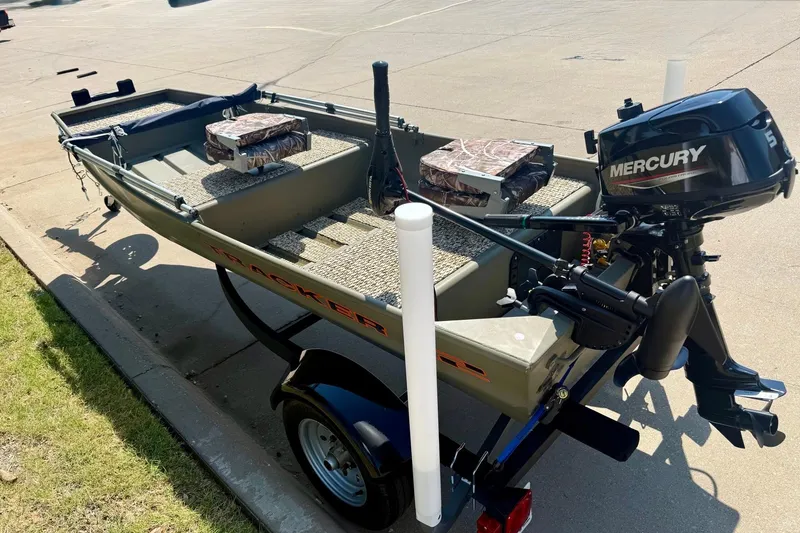 Slide: The Image of 2026 Tracker Grizzly 12 Jon boat with Mercury motor on trailer, parked outdoors. - 4