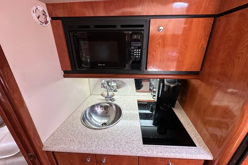 Slide: The Image of Compact kitchen area in a 2005 Fountain 48 Express Cruiser with microwave, sink, and stovetop. - 27