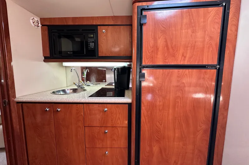 Slide: The Image of Compact kitchen in 2005 Fountain 48 Express Cruiser with wood cabinetry and modern appliances. - 26