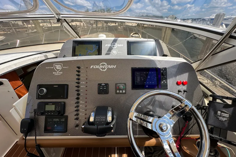 Slide: The Image of 2005 Fountain 48 Express Cruiser helm with navigation screens and controls, docked at marina. - 19
