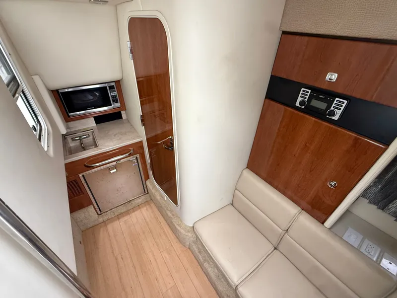 Slide: The Image of Interior of a 2014 Formula 350 Crossover Bowrider with seating area, microwave, and wood paneling. - 24