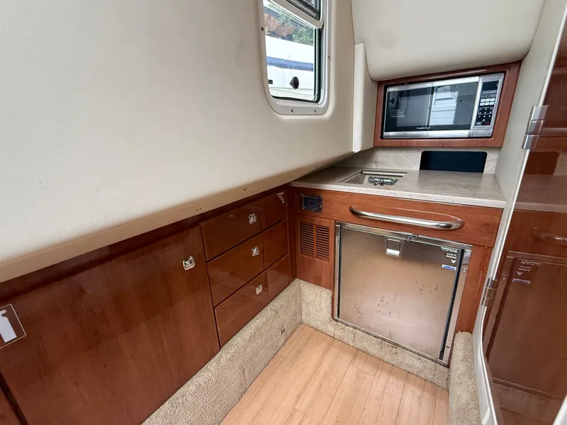 Slide: The Image of Interior of a 2014 Formula 350 Crossover Bowrider with wood cabinetry, microwave, and refrigerator. - 25
