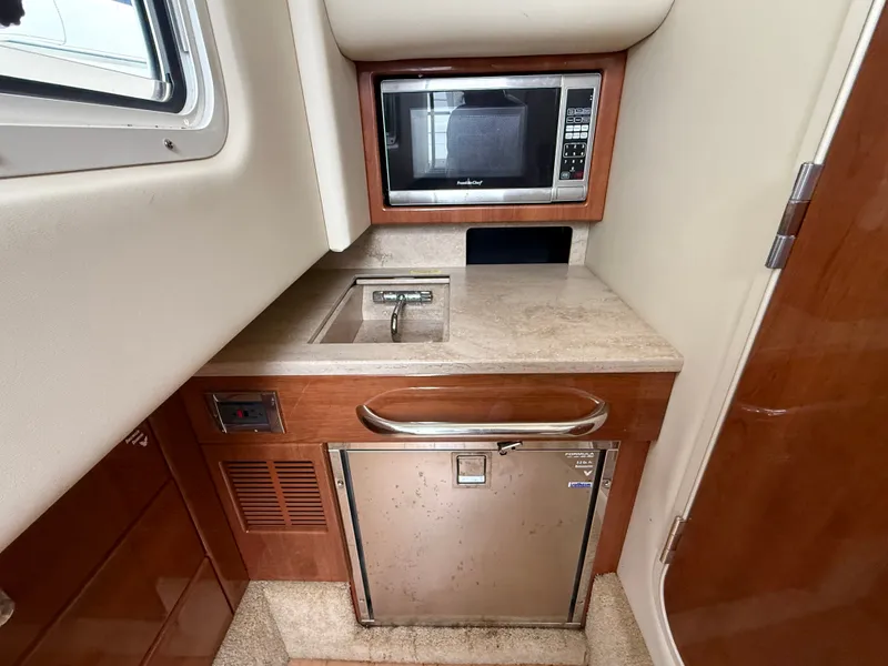 Slide: The Image of The 2014 Formula 350 Crossover Bowrider's galley features a sink, microwave, and refrigerator. - 26
