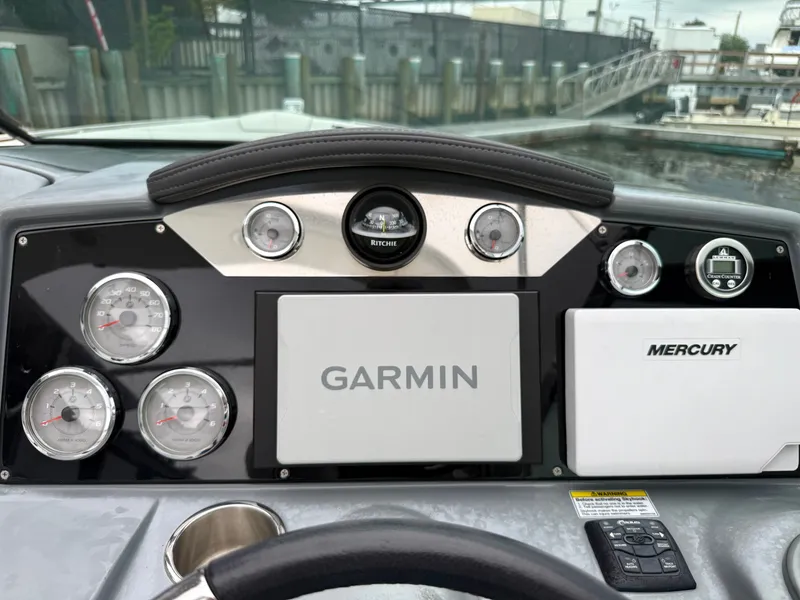 Slide: The Image of The dashboard of a boat featuring Garmin and Mercury devices, surrounded by multiple gauges. - 18