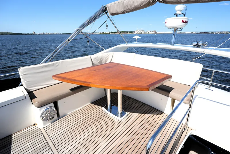 Slide: The Image of Luxury 2013 Prestige 500 yacht deck with wooden table and cushioned seating, overlooking serene waters. - 28