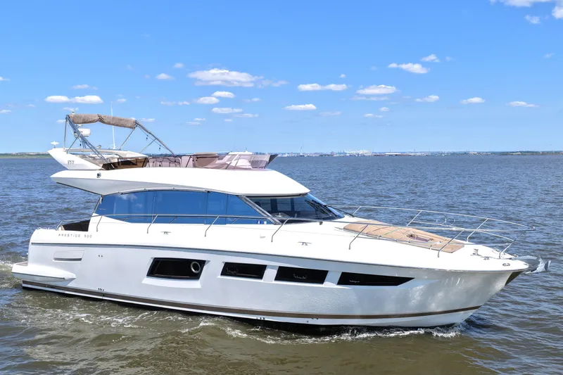 Slide: The Image of 2013 Prestige 500 yacht cruising on open water under a clear blue sky. - 5