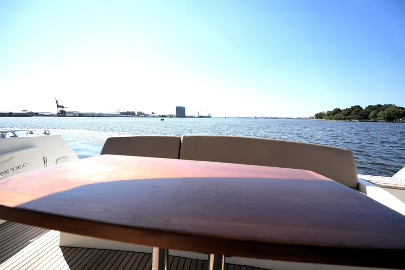 Slide: The Image of Luxury yacht Prestige 500, 2013 model, with scenic waterfront view and wooden table. - 22