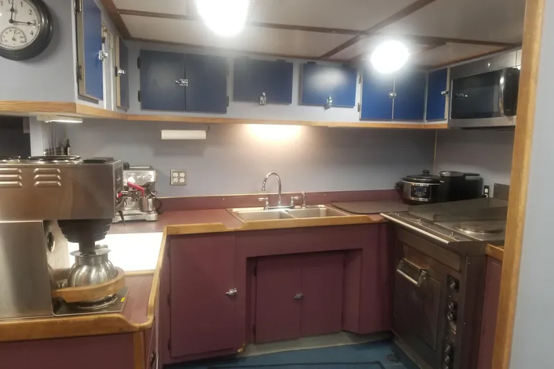 Slide: The Image of 1974 Custom Steel Cannery Tender kitchen with modern appliances and blue cabinets. - 5