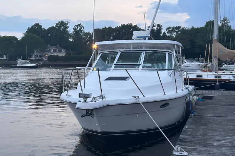 Slide: The Image of 2004 Tiara 2900 boat docked at a marina, surrounded by calm water and trees. - 16