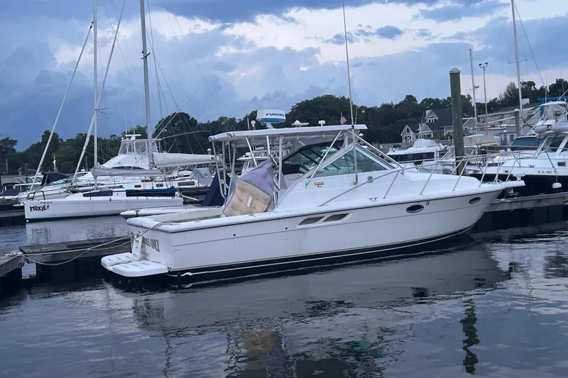 Slide: The Image of 2004 Tiara 2900 boat docked in a marina, surrounded by other vessels under a cloudy sky. - 2