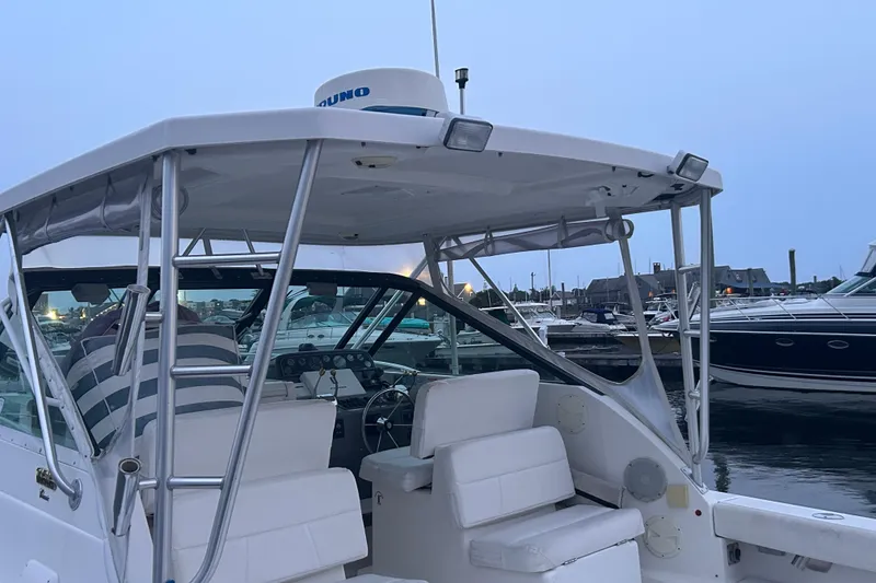 Slide: The Image of 2004 Tiara 2900 boat docked at marina, featuring white seating and canopy. - 9