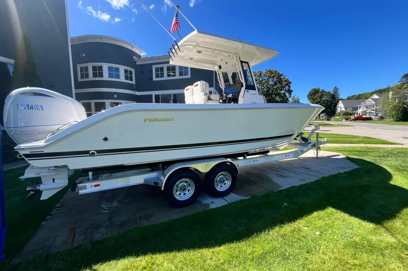 The Image of 2027 Pursuit S 268 Sport boat on trailer, parked outdoors under clear blue sky. - 0
