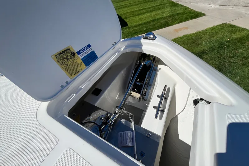 Slide: The Image of Anchor compartment of 2027 Pursuit S 268 Sport boat, open lid, grassy background. - 9